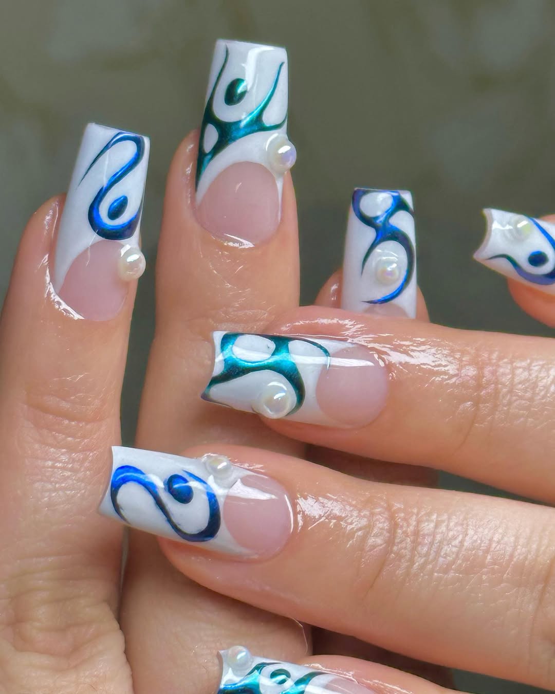 a person wearing french manicure with a blue chrome design