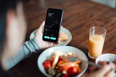 woman checking stock market date using mobile app on smart phone while having breakfast representing European ETF flows