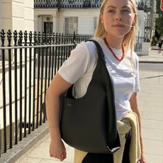Woman wears white tee, black trousers, black shoulder bag