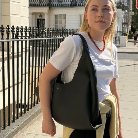 Woman wears white tee, black trousers, black shoulder bag