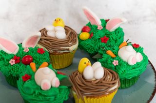 A plate with some Easter cupcakes decorated with carrots and bunny ears.
