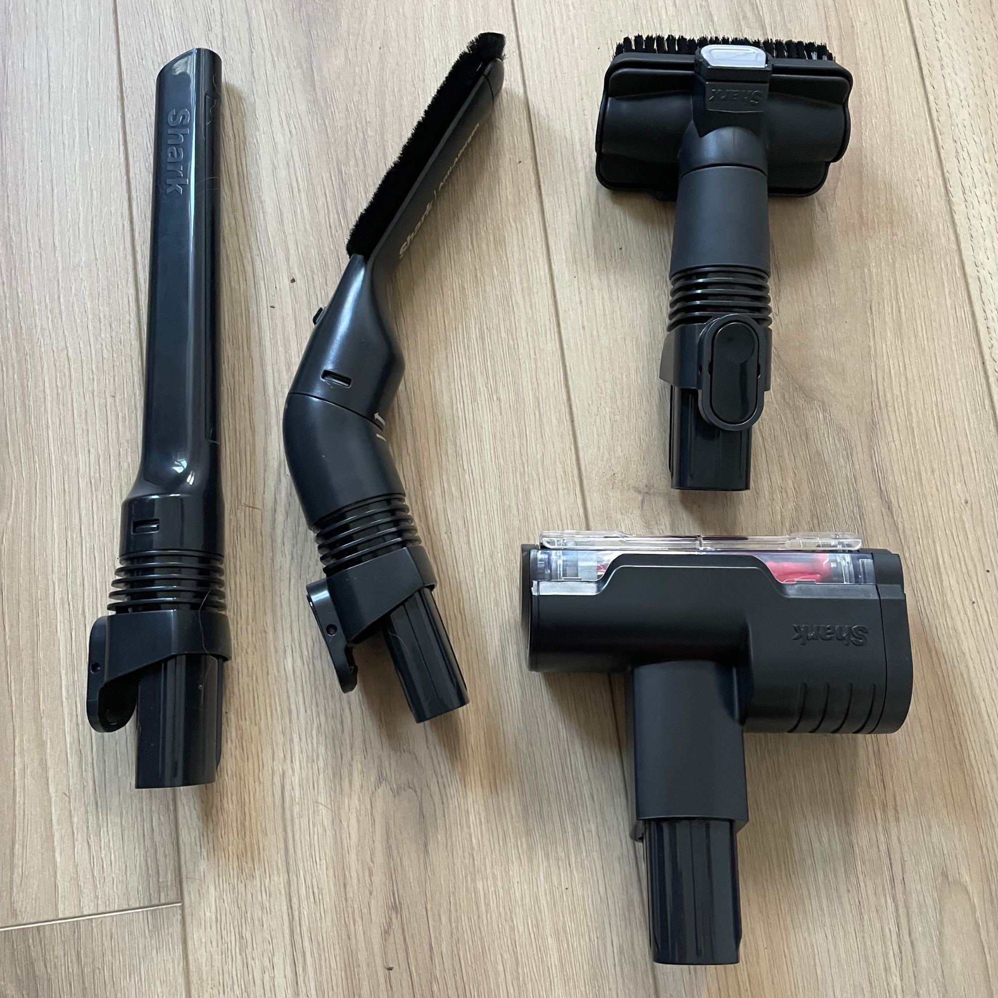 Attachments of the Shark Stratos Cordless Vacuum laying on wood-effect flooring