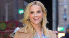 Reese Witherspoon, wearing a blue shirt and camel coat, smiles on January 29, 2025 in New York City