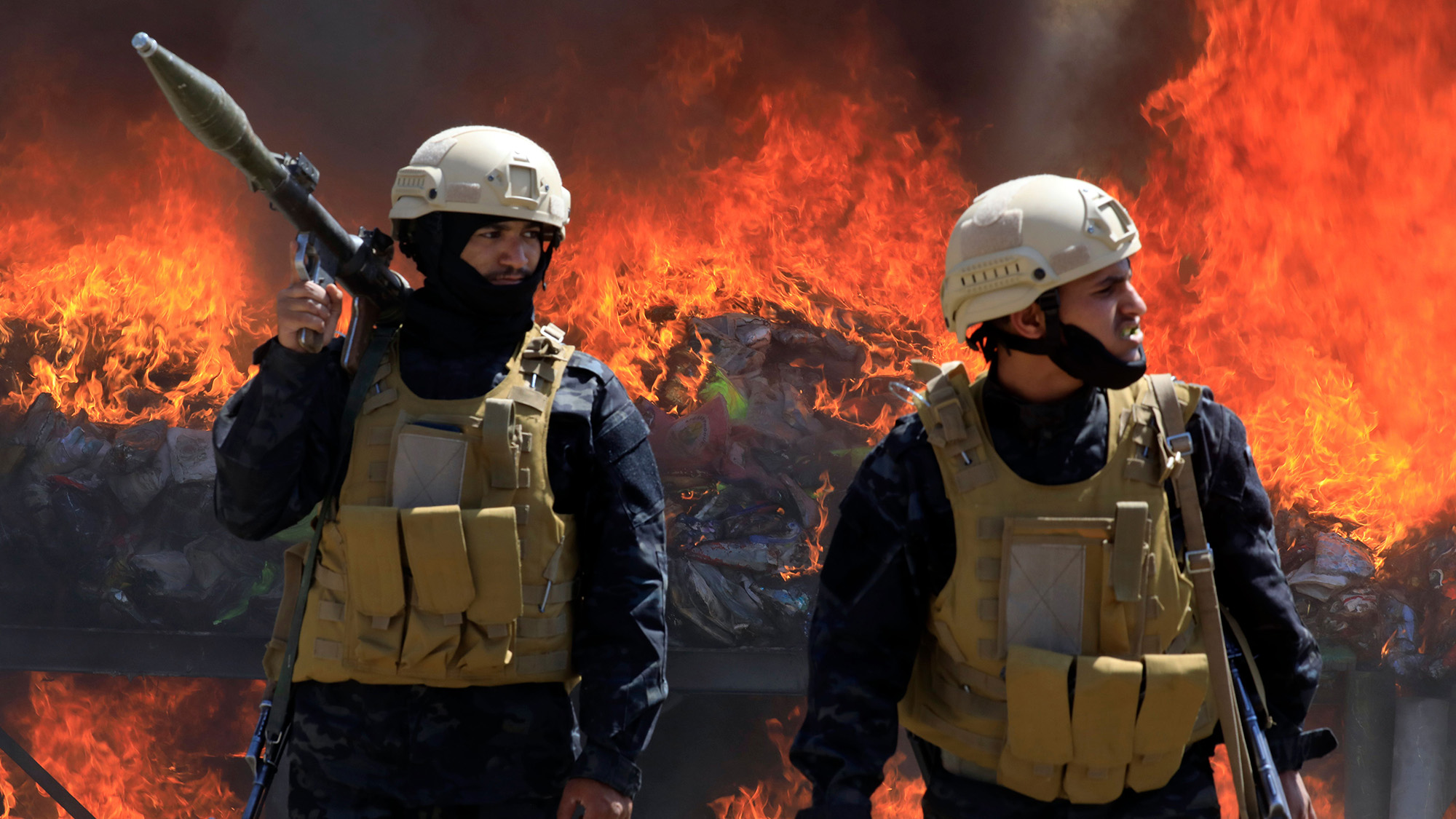 Houthi security personnel keep watch in front of a burning pile of confiscated narcotics in Yemen