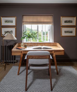 office with mauve brown walls. mid century desk and chair, striped blind and patterned rug
