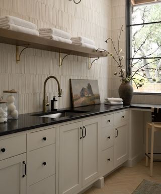 laundry room with neutral cabinets, textured walls and black countertops