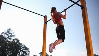 Woman performs a chin up outdoors