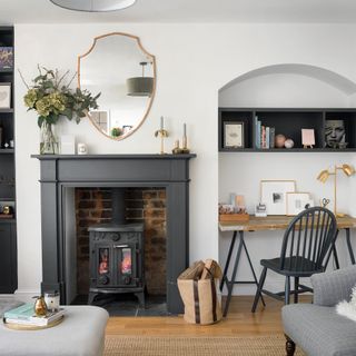 White living room with stove in black fireplace and desk in alcove
