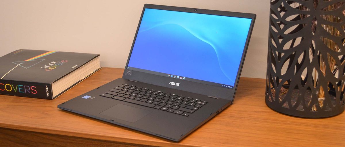 The Asus Chromebook CX1500 sitting open on a wooden side table against a wall