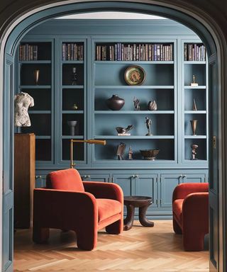 Blue living room with red arm chair and bookshelves
