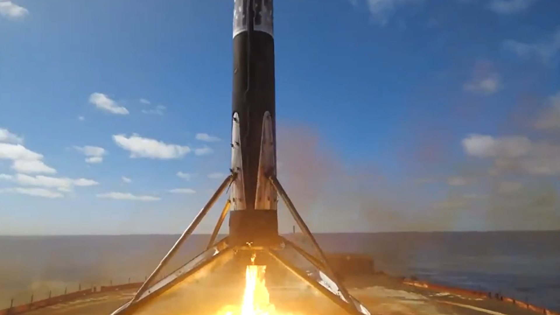 a white rocket stands upright on a barge at sea