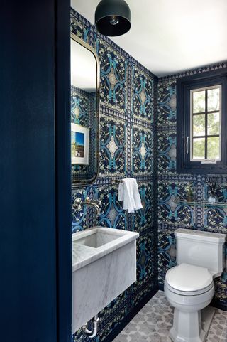 maximalist powder room with printed blue wallpaper and tiled floors by Zoe Feldman