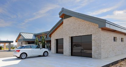Glazed sectional garage door on modern home exterior with light colored paved driveway