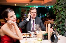 Man on his phone while dining with an annoyed woman.