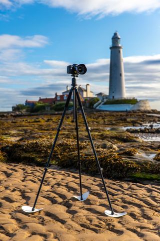 Tripod on sand with lighthouse in the distance