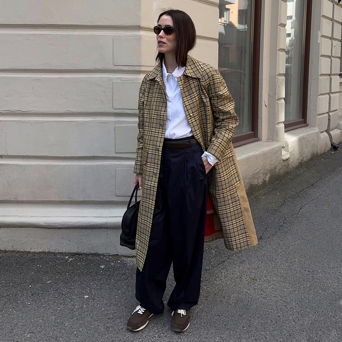 Annabel wears a plaid jacket, white top, black pants, and brown sneakers.