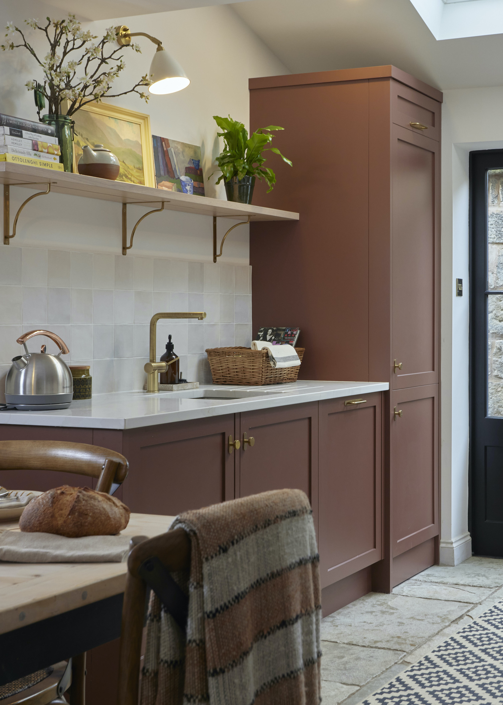 kitchen in brown with open shelving with a plant, painting and kitchen essentials on top.