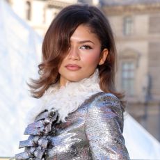 Zendaya arrives at Louis Vuitton's paris fashion week show wearing a metallic dress with a feathered collar