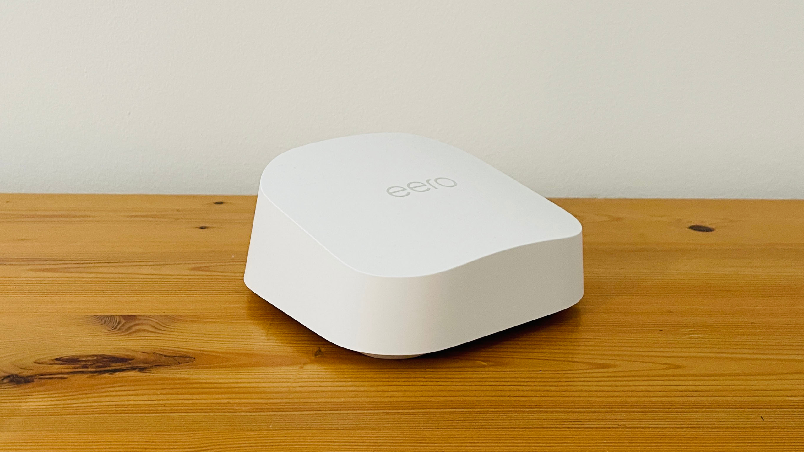 Eero 7 grid Wi-Fi system rests on wooden table