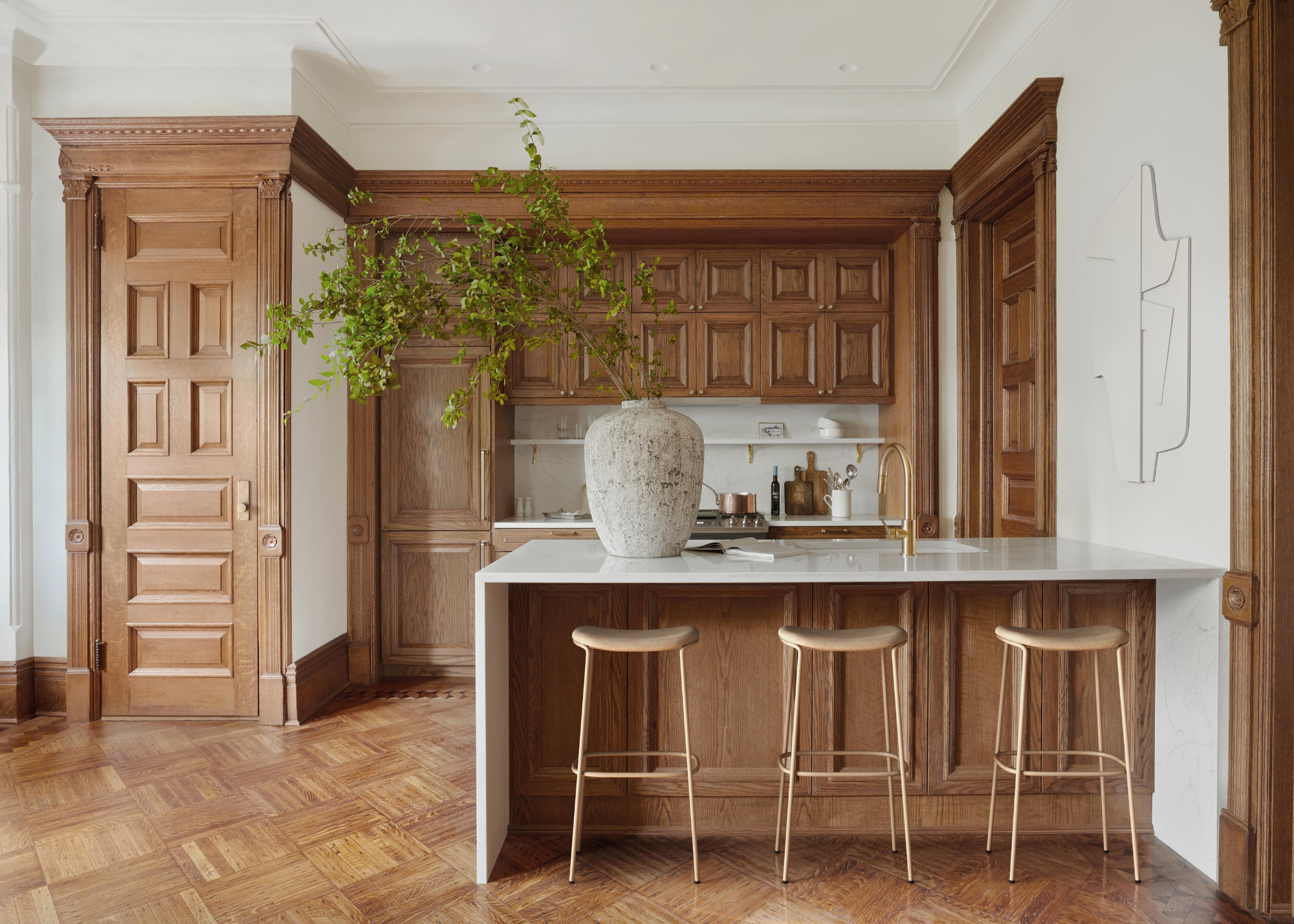 An all wood panelled kitchen with matching doors and floor, white walls, and a marble countertop