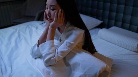 A woman sitting up in bed with her head in her hands