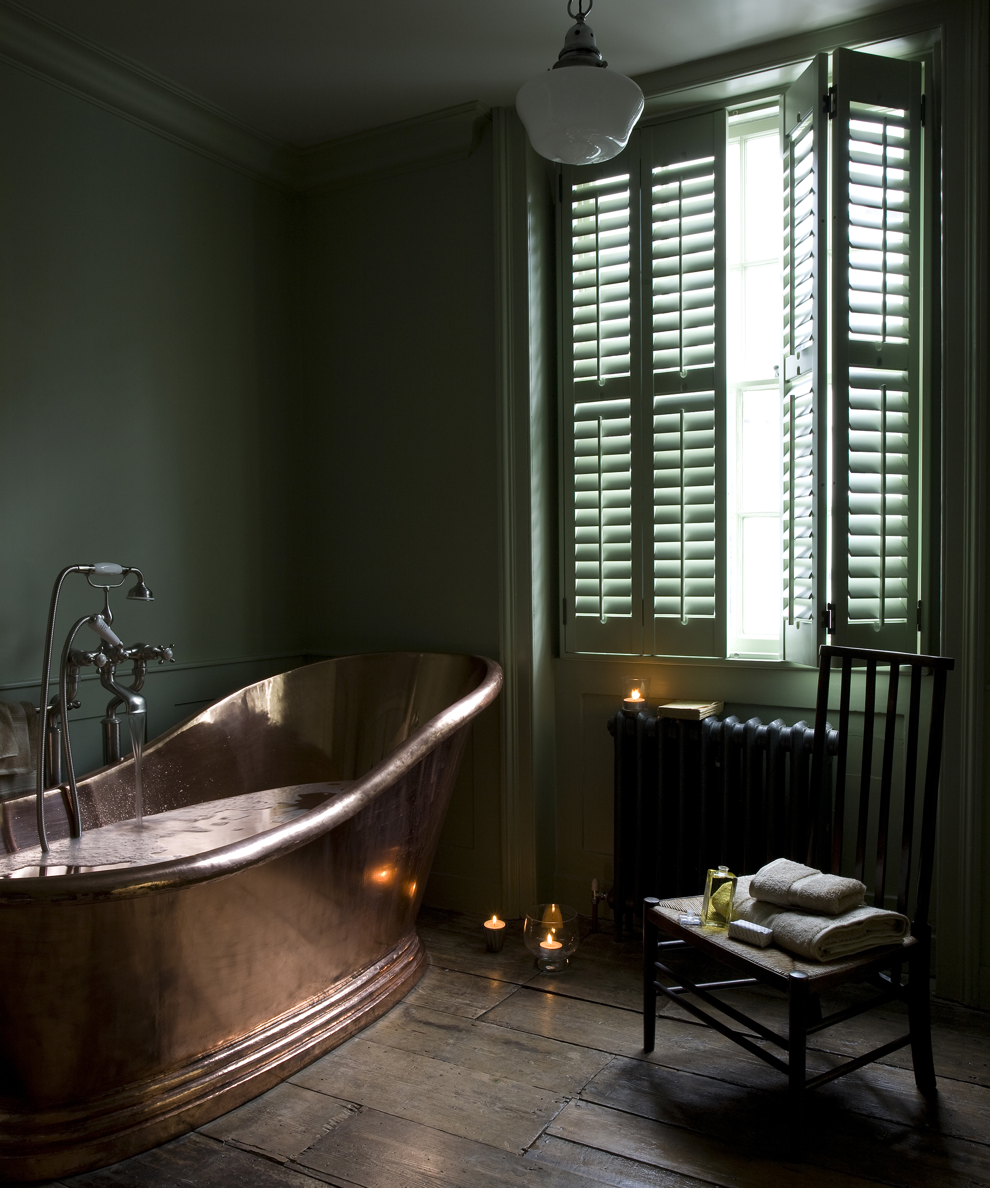 Freestanding copper bath with window shutters in bathroom