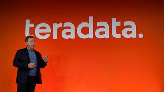 Steve McMillan, CEO at Teradata, speaking onstage at Teradata Possible 2024 in London. Behind him, the word "teradata." is shown on a large orange backdrop.