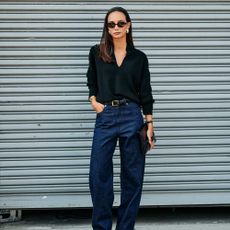 Woman in dark-wash jeans and a collared black blouse. 