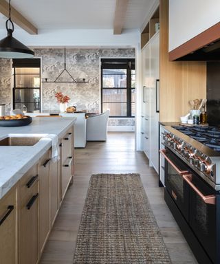 Wooden kitchen with a dining table area and cloud mural on one wall