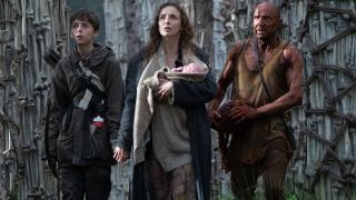 Alfie Williams, Jodie Comer, and Ralph Fiennes look up in awe among towers of bones in 28 Years Later.