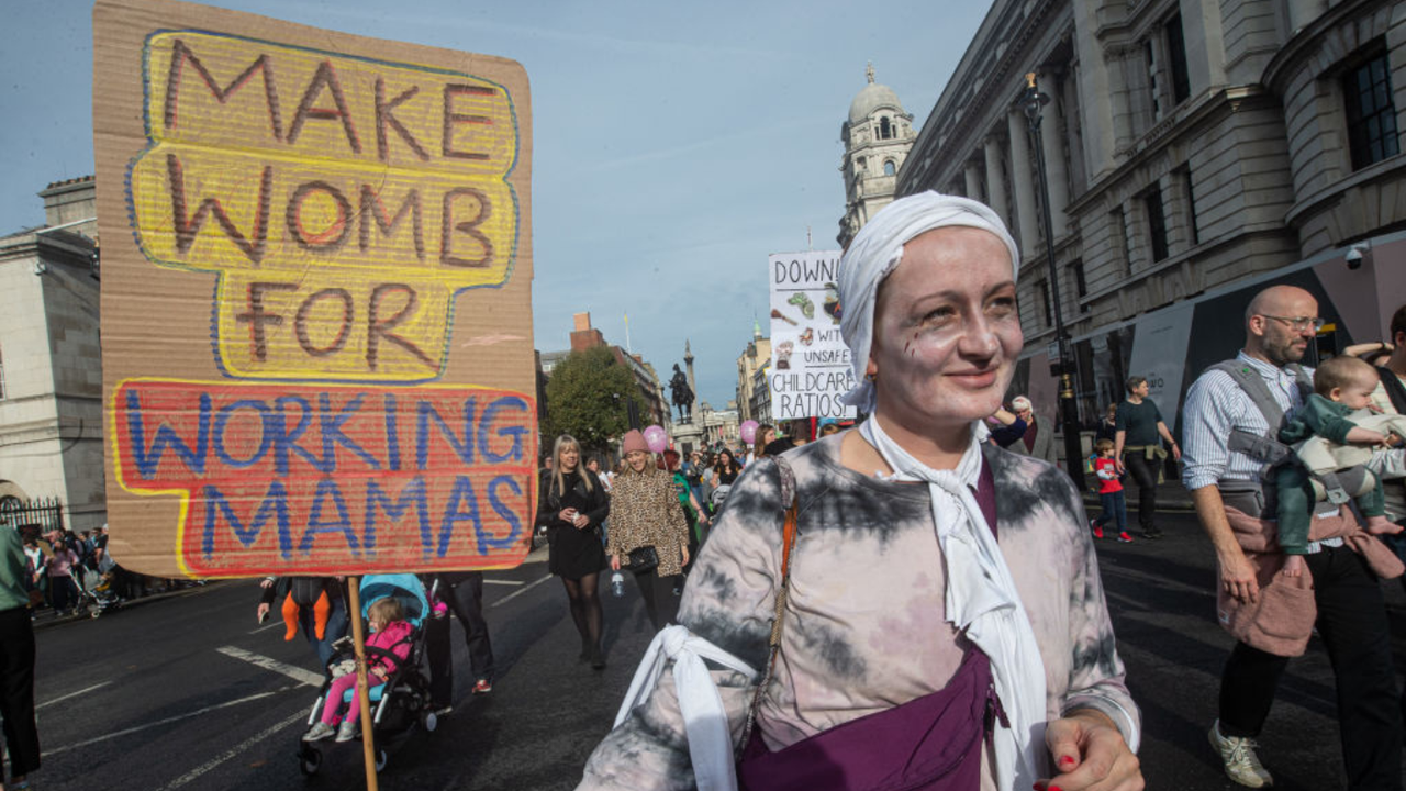 A protester clad in a Halloween costume holds a sign saying &amp;#039;make womb for working mamas&amp;#039;