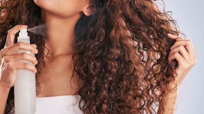Woman spraying product onto her curly hair