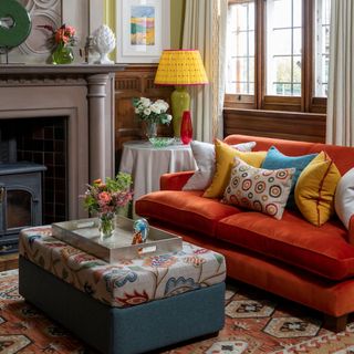 Living room with patterned rug, fabric ottoman table and orange sofa