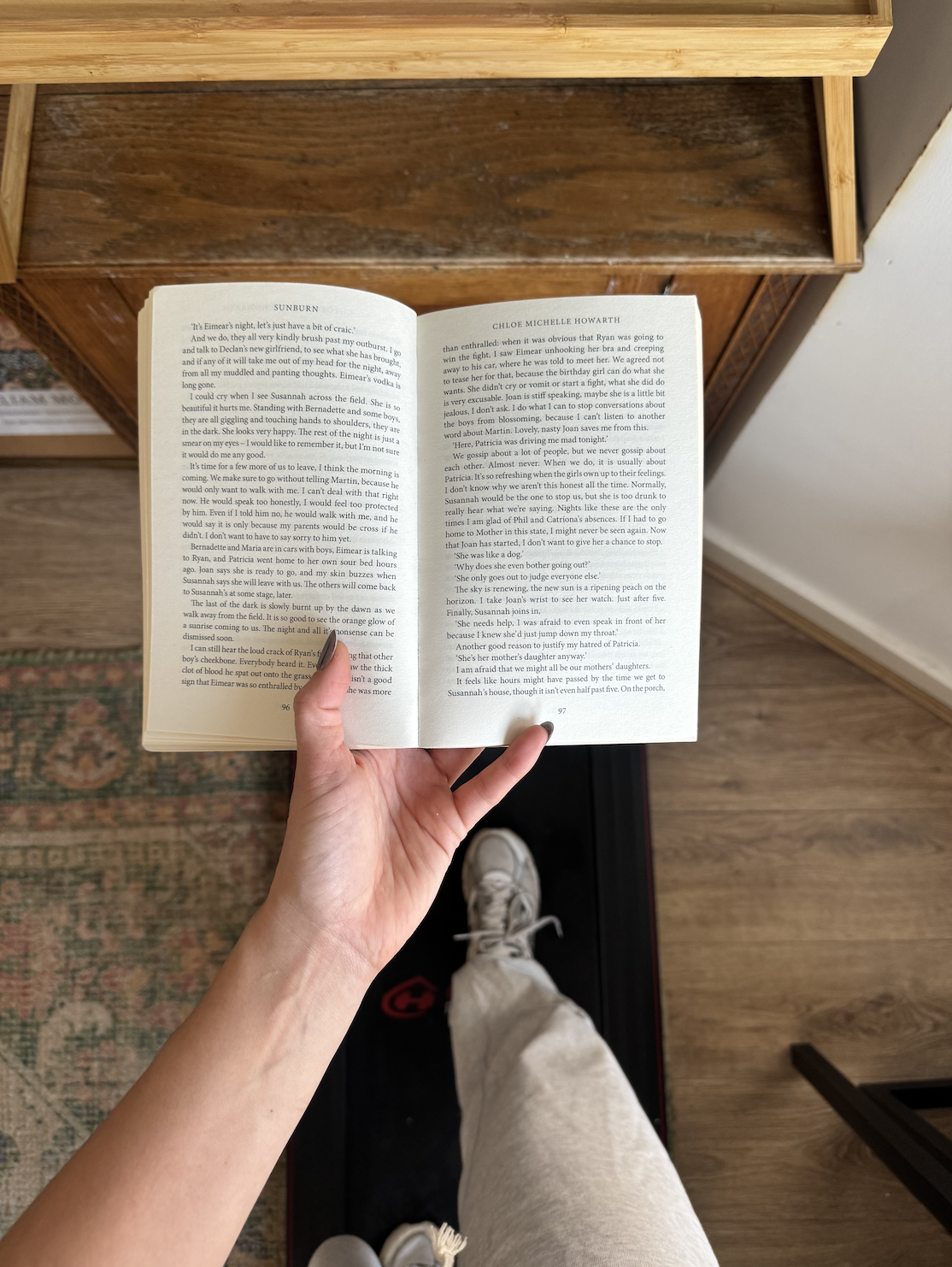 Person holding an open book whilst walking on treadmill