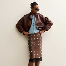 A model wearing a brown bomber jacket, blue cardigan and polka dot skirt from New Look.