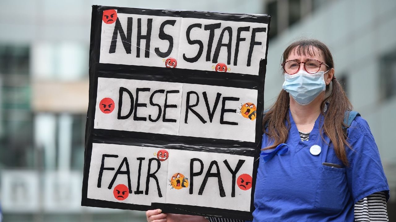 Nurse protesting with placard reading &amp;#039;NHS staff deserve fair pay&amp;#039;