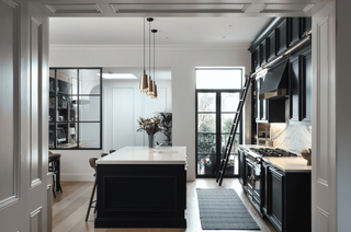 black and white traditional kitchen with gold lighting and ladder