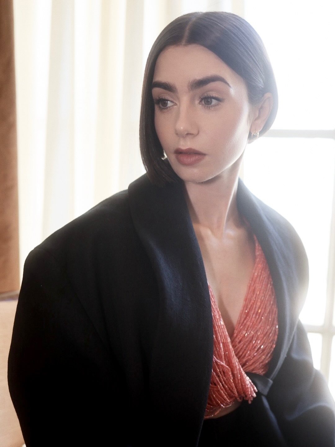 Lily Collins wearing a black blazer with an asymmetrical bob hairstyle
