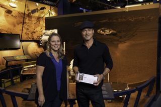 Actor Brad Pitt (right) shows off his Mars "boarding pass" with Jennifer Trosper (left), the Mars 2020 project systems engineer, at JPL on Sept. 6, 2019.