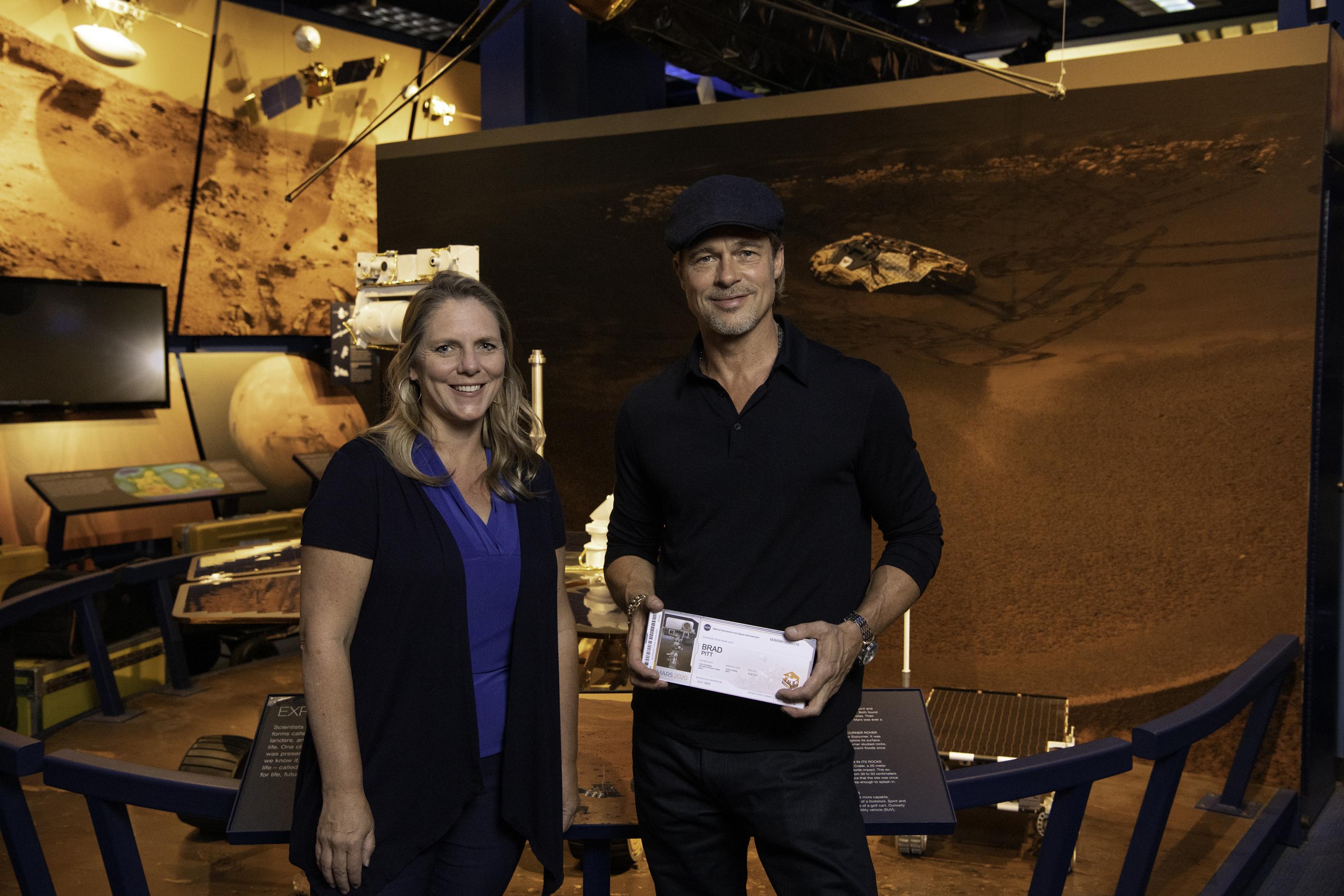 Actor Brad Pitt (right) shows off his Mars "boarding pass" with Jennifer Trosper (left), the Mars 2020 project systems engineer, at JPL on Sept. 6, 2019.