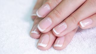 Two hands with a micro French manicure