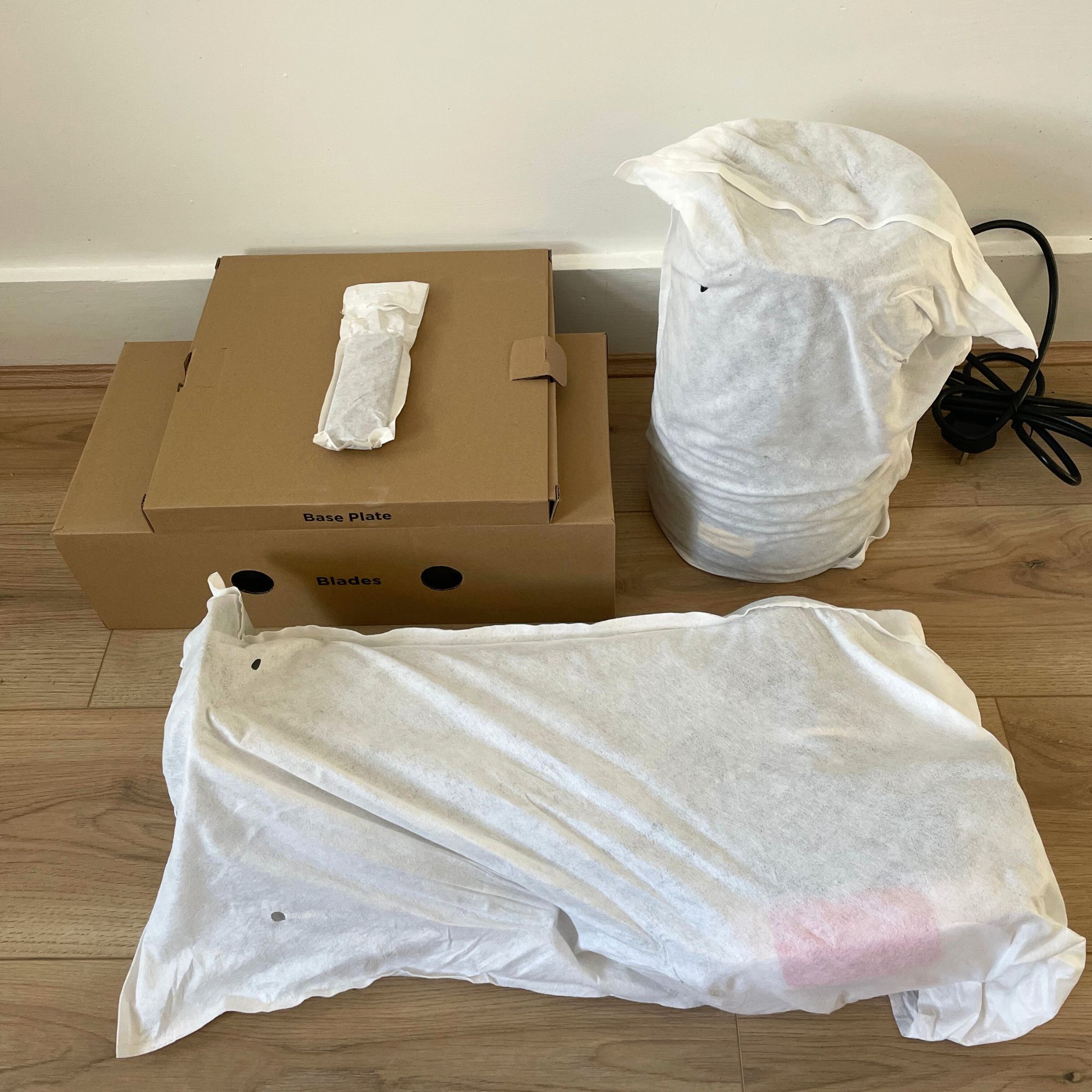 Components of Shark TurboBlade Cool + Heat TH200UK in packaging, laying on wood-effect flooring