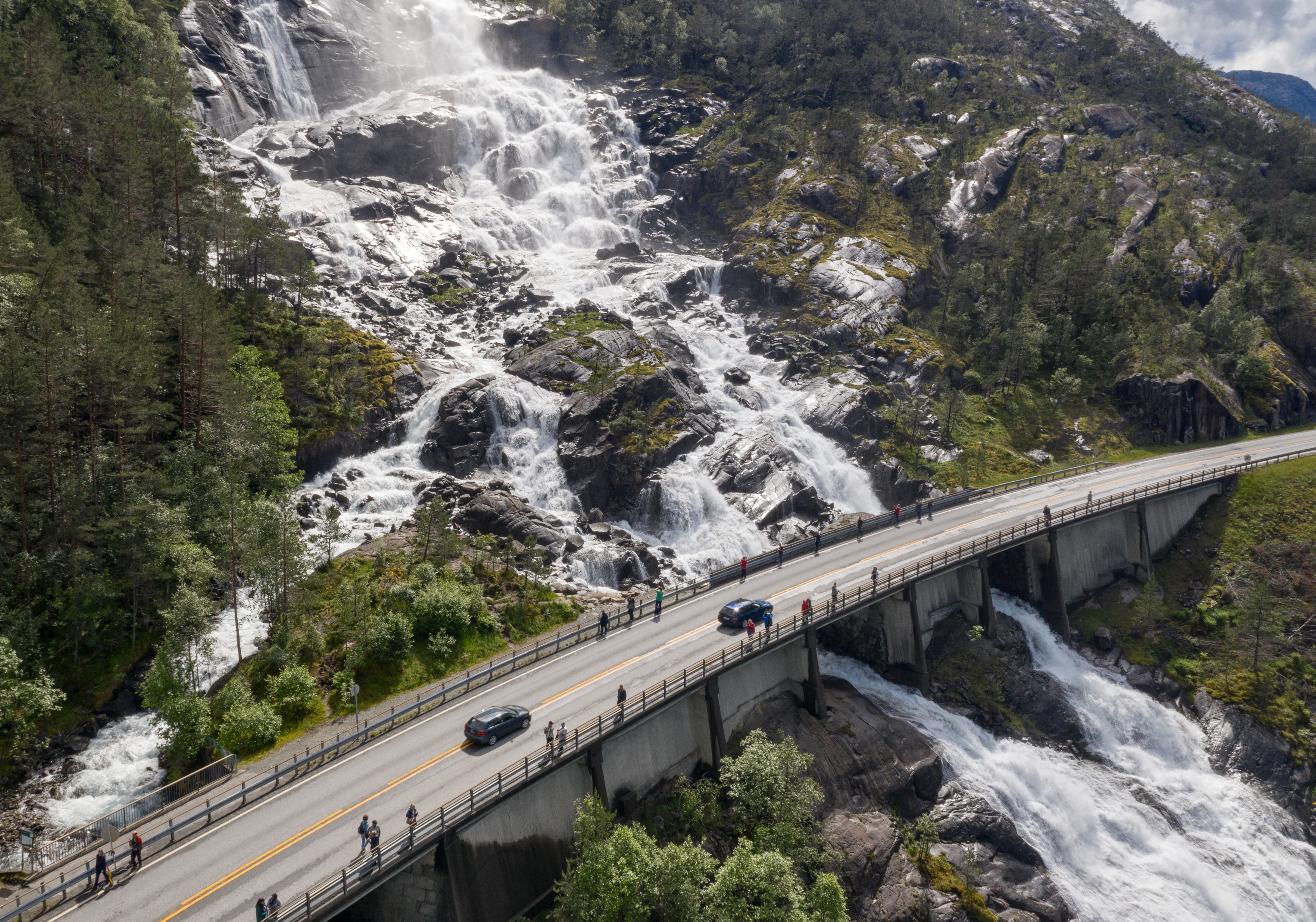 Cars on a bridge go across the Langfossen waterfall in Norway