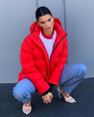 A photo of Kendall Jenner bundling up in a cropped cherry red Super Puff.