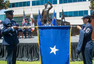 Space Force Chief Master Sgt. Willie Frazier (at left) and Air Force Chief Master Sgt. Sarah Morgan unfurl the brigadier general officer's flag during retired Air Force Brig. Gen. Buzz Aldrin's promotion ceremony at the Space Systems Command courtyard in Los Angeles on May 5, 2023.