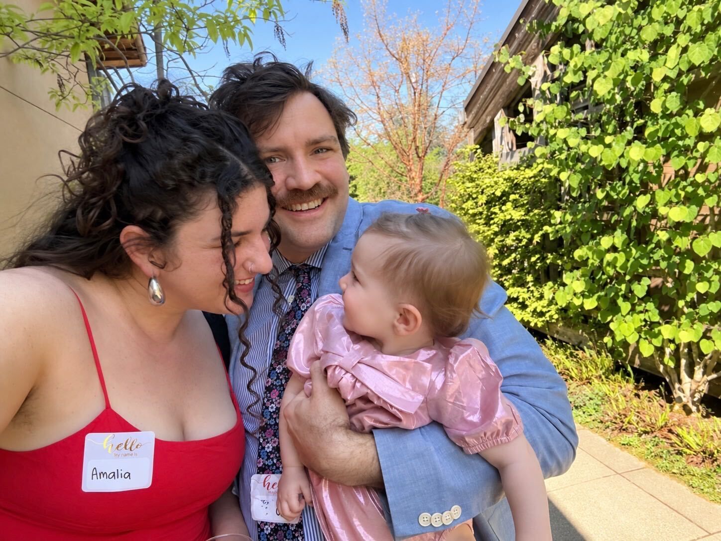 Amalia Bob-Waksberg smiling with her husband and young daughter outdoors.