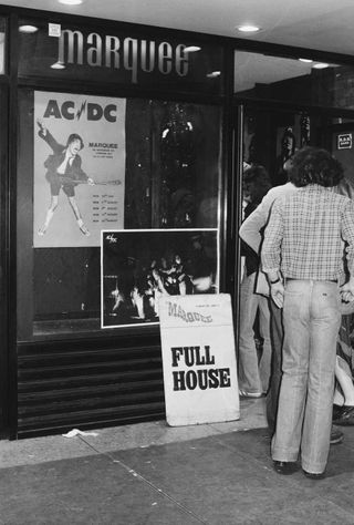 Outside the Marquee Club on Wardour Street, with a poster advertising AC/DC's residency in the window