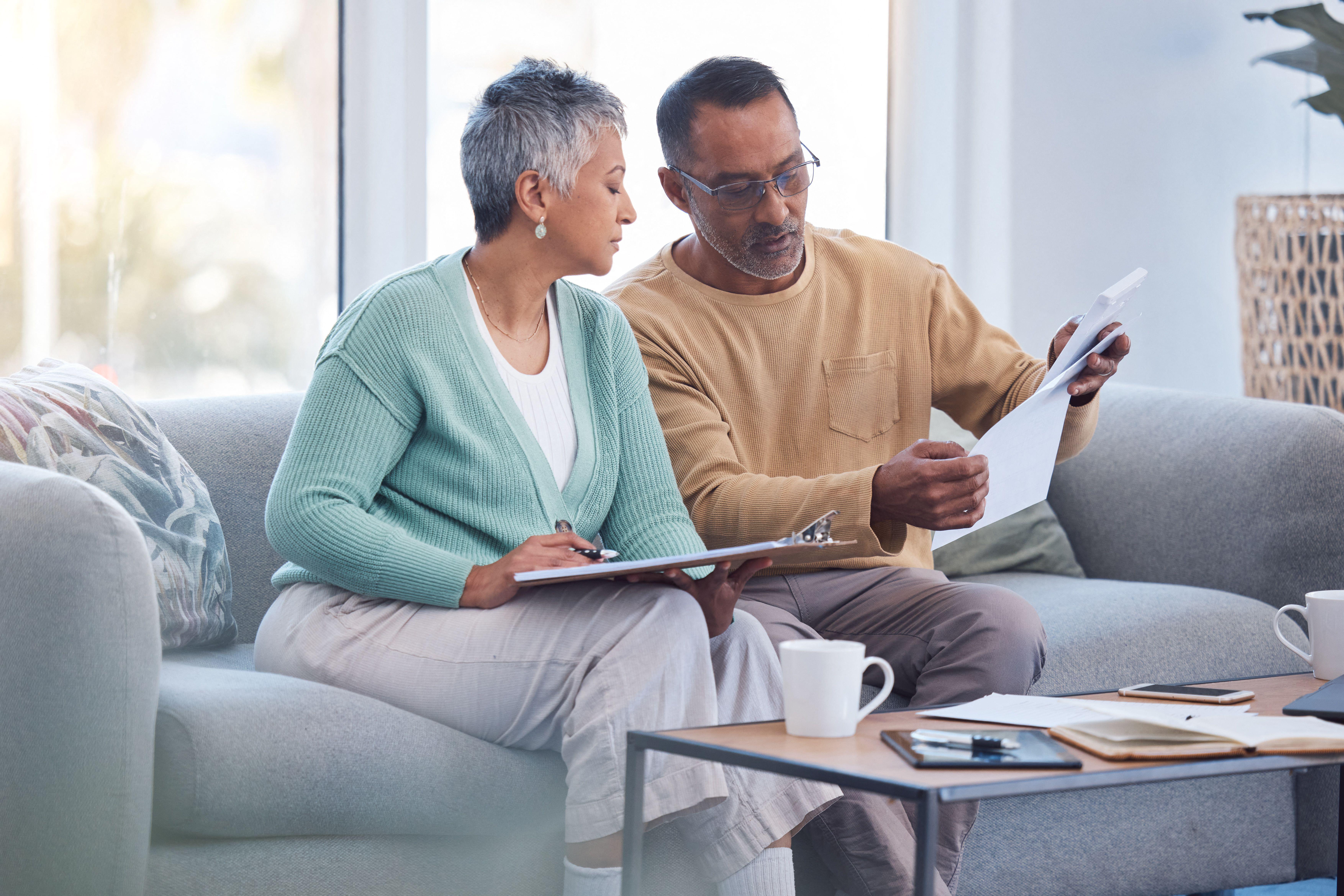 2KWE98H Finance, documents and senior couple on sofa with bills, paperwork and insurance checklist in home, life or asset management.