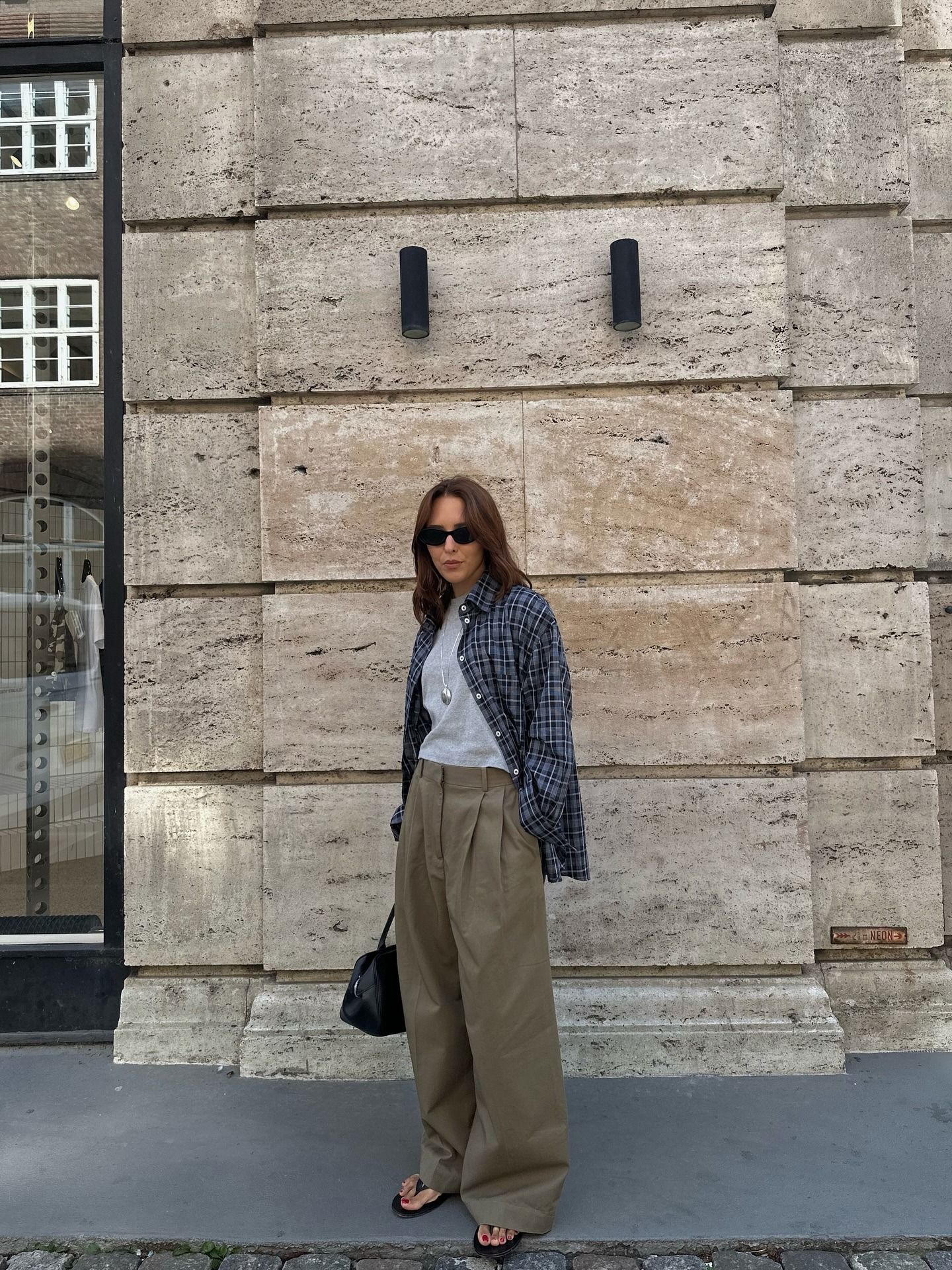 Woman wears khaki cargo trousers, grey t-shirt and plaid shirt
