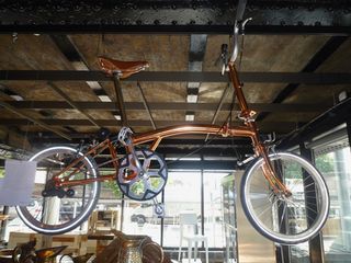 A copper-plated bike hanging off the ceiling in a show room